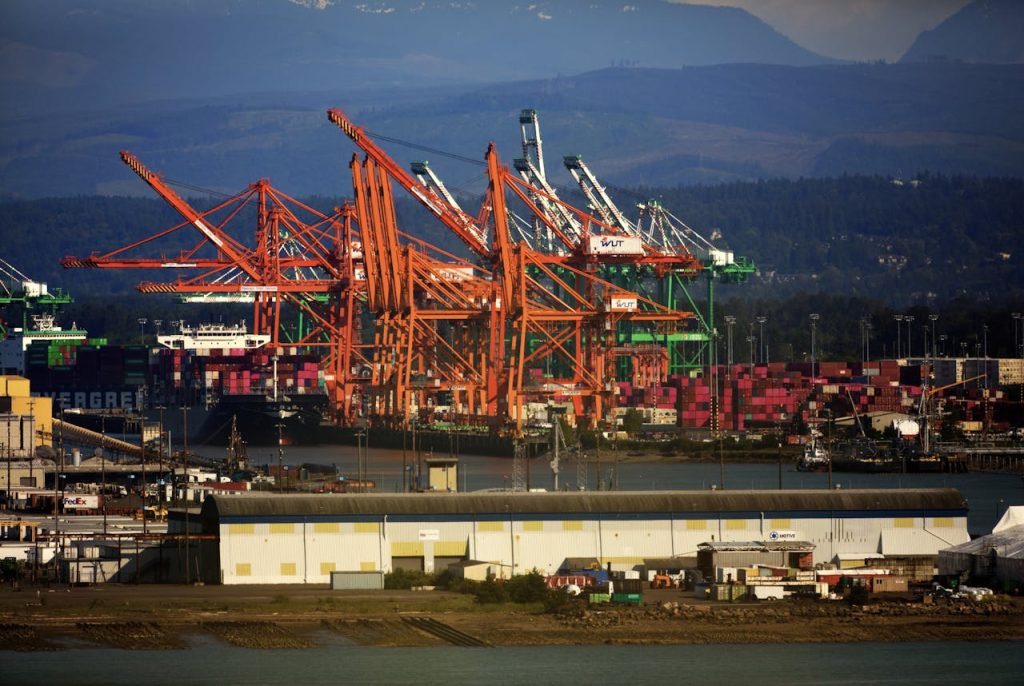 An array of colorful cargo cranes and containers in Port of Tacoma under a clear sky.